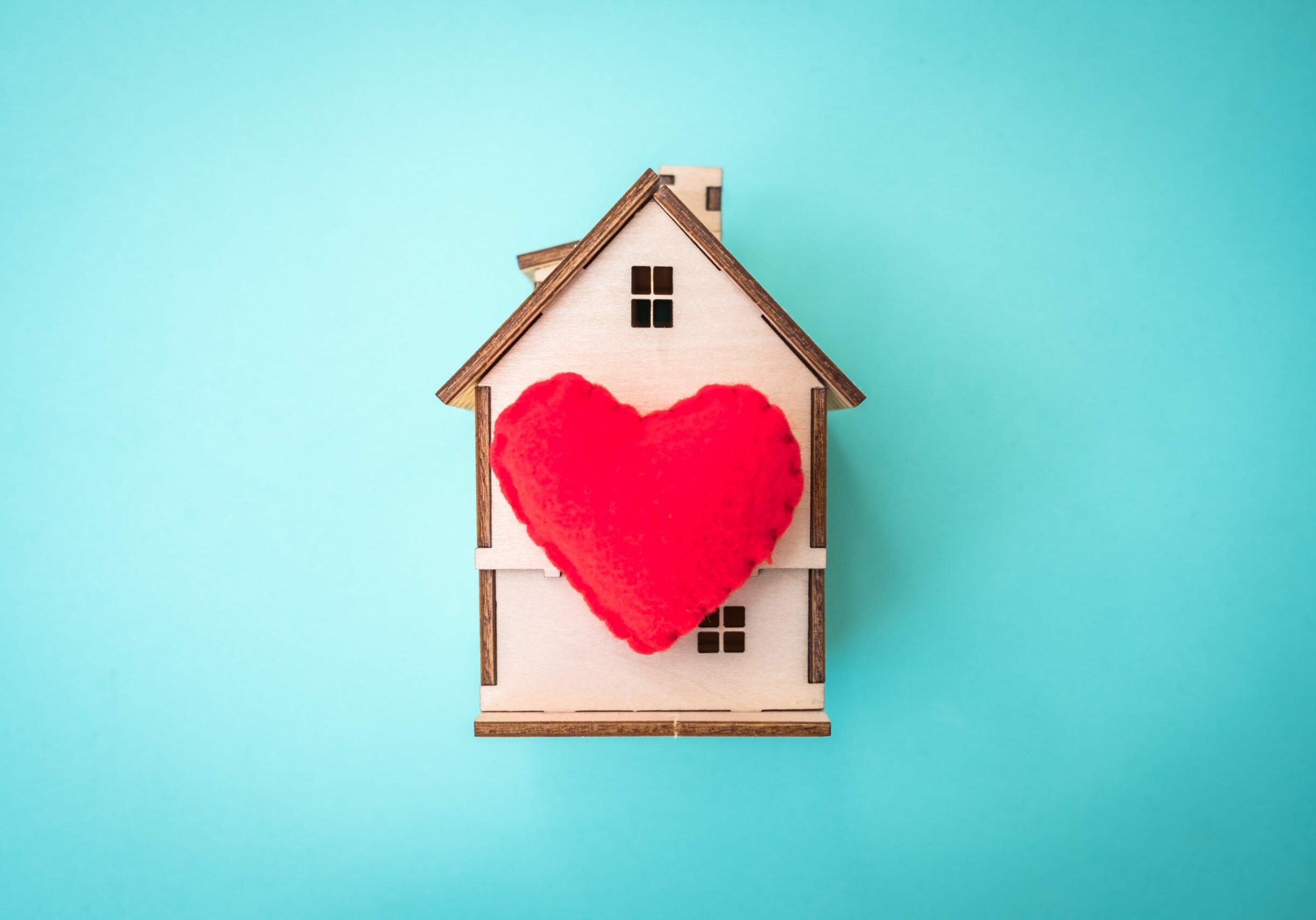 Ein Spielzeughaus aus Holz mit einem roten Herz-Kissen auf der Front